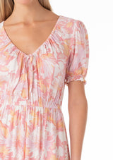 [Color: Peach/Light Pink] A close up front facing image of a blonde model wearing a classic spring bohemian maxi dress in a peach pink floral print. With short puff sleeves, a front slit, an elastic waist, and a drawstring v neckline with adjustable tie. 