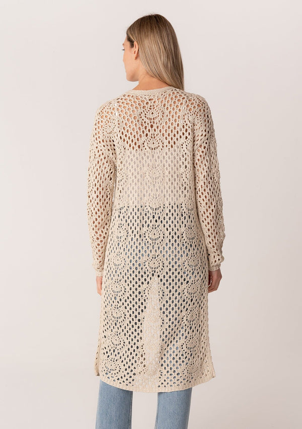 [Color: Natural] A back facing image of a blonde model wearing a classic bohemian cream colored mid length crochet cardigan.