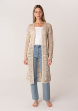 [Color: Natural] A front facing image of a blonde model wearing a classic bohemian cream colored mid length crochet cardigan.