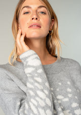[Color: Heather Grey/Cream] A model wearing a fuzzy grey sweater in an abstract animal print. With a slightly cropped length, long sleeves, and a round neckline.