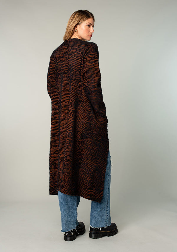 [Color: Cocoa Zebra] Ultra soft and fuzzy statement cardigan in a subtle allover cocoa brown and black zebra print. A duster length sweater featuring oversize front patch pockets.
