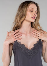 [Color: Pewter] A close up front facing image of a blonde model wearing a pewter grey lace trim camisole with a v neckline, adjustable spaghetti straps, and a flowy relaxed fit.