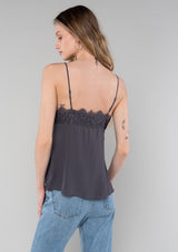 [Color: Pewter] A back facing image of a blonde model wearing a pewter grey lace trim camisole with a v neckline, adjustable spaghetti straps, and a flowy relaxed fit.