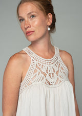 [Color: Vanilla Bean] A model wearing a cream colored crochet yoke tank top with a racerback and a flowy fit.
