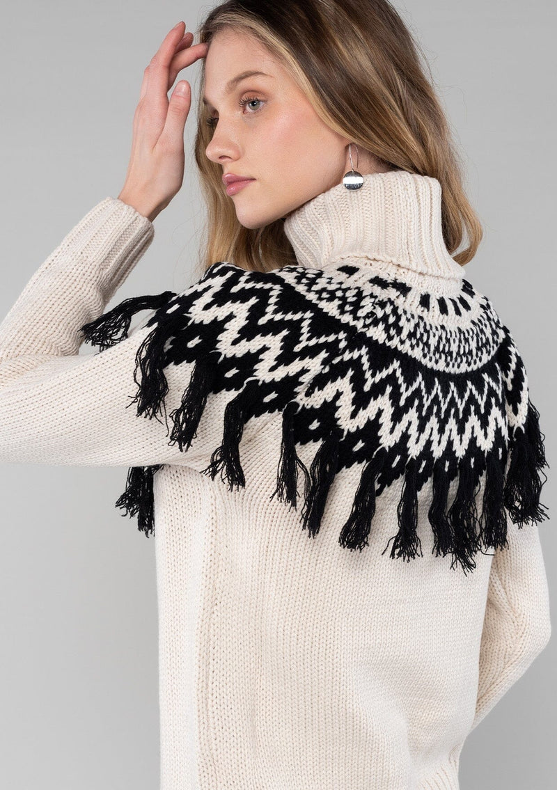 [Color: Ivory/Black] A cozy ski sweater with a bohemian twist. Featuring a warm turtleneck and a contrast knit yoke design and a fringed detail in front and back.
