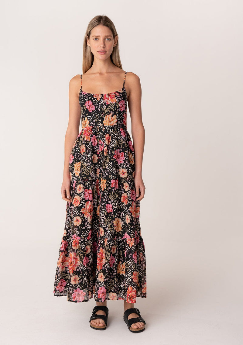 [Color: Black/Fuchsia] A front facing image of a blonde model wearing a pretty spring maxi dress in a black and pink floral print. With spaghetti straps, a scooped neckline, a flowy tiered skirt, a button front, and a half smocked elastic bodice at the back. 