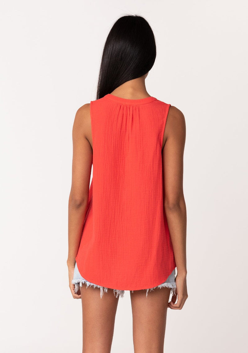 [Color: Flame] A back facing image of a brunette model wearing a simple bright red cotton tank top with a button front, a v neckline, and a relaxed fit. 