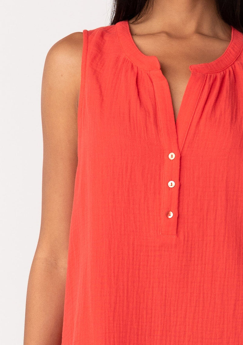 [Color: Flame] A close up front facing image of a brunette model wearing a simple bright red cotton tank top with a button front, a v neckline, and a relaxed fit. 