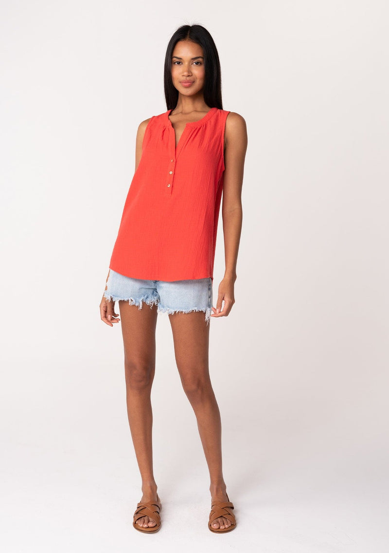 [Color: Flame] A full body front facing image of a brunette model wearing a simple bright red cotton tank top with a button front, a v neckline, and a relaxed fit. 