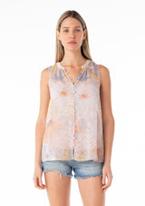 [Color: Natural/Blue] A front facing image of a blonde model wearing a pretty spring chiffon tank top designed in a pink and blue floral print. With a self covered button front, a button loop trimmed split v neckline, and a relaxed fit. 