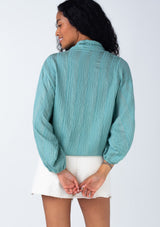 [Color: Dusty Teal] A back facing image of a brunette model wearing a best selling bohemian tie front resort top in a dusty teal shadow stripe. With voluminous long sleeves and a tie front detail that can be styled in multiple ways.