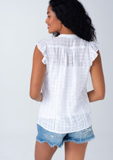 [Color: White] A back facing image of a brunette model wearing a white cotton textured gingham top. With short flutter cap sleeves, a self covered button front, a tassel tie neckline, and lace trim. 