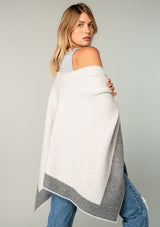 [Color: Heather Natural/Heather Grey] A back facing image of a blonde model wearing a soft and warm mid length sweater cape. An open front cape cardigan with a contrast border design. Perfect fall sweater, great for layering. 