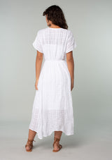 [Color: White] A full body back facing image of a brunette model with wearing a white cotton button front maxi dress with short sleeves and an allover textured gingham.
