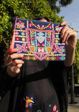 [Color: Multi] Woman holding a colorful floral embroidered clutch.