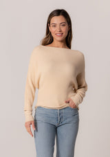 [Color: Cream] A front facing image of a brunette model wearing a cream waffle knit pullover sweater. With long sleeves, a relaxed fit, and a wide neckline that can be worn off the shoulder.