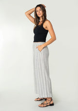 [Color: White/Black] A front facing image of a brunette model wearing a bohemian wide leg lounge pant in a white and black stripe. With side pockets and an elastic waistband. 