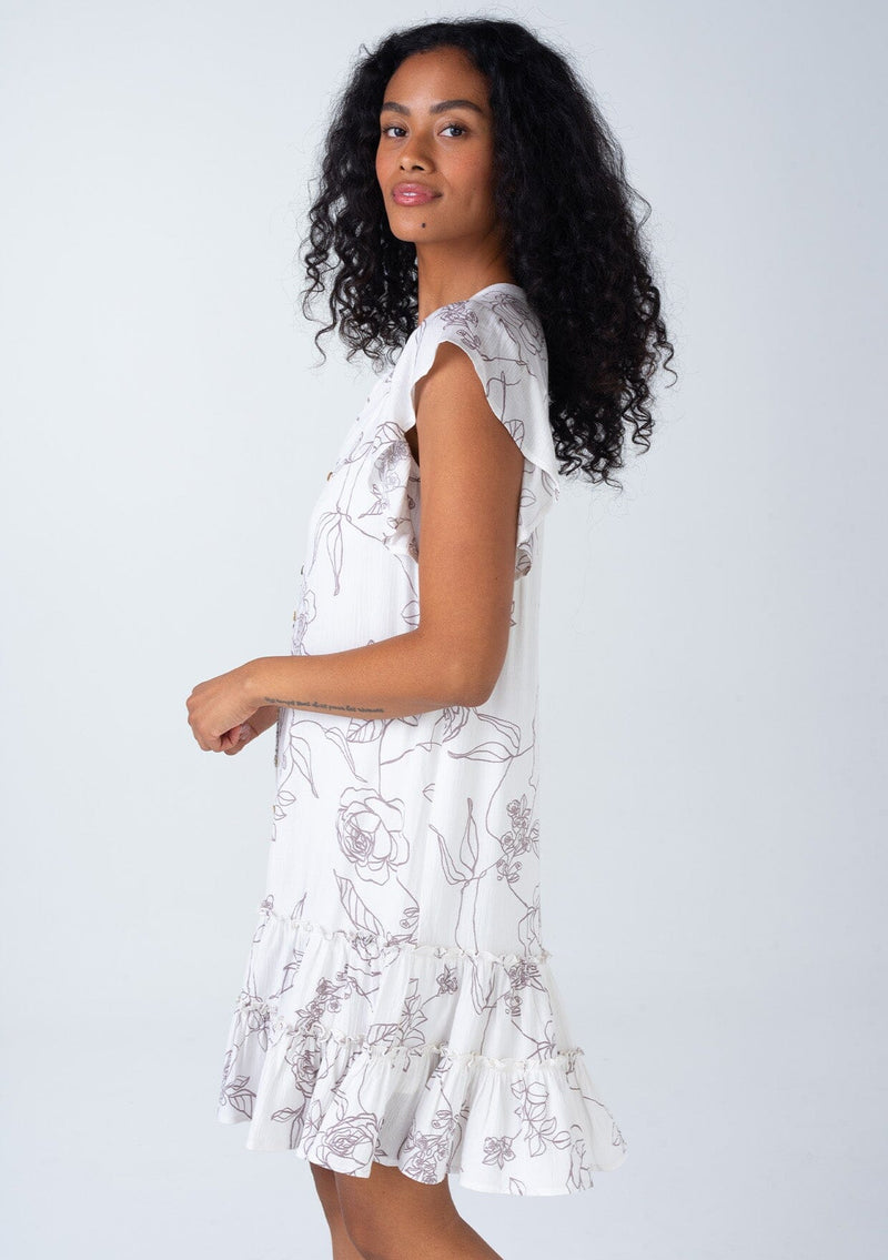 [Color: Natural/Taupe] A side facing image of a brunette model wearing a bohemian spring mini dress in an off white and taupe floral print. With short flutter sleeves, a button front, a ruffle trimmed tiered skirt, and a loose relaxed fit. 