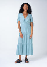 [Color: Dusty Blue] A front facing image of a bohemian dusty blue mid length dress. With short puff sleeves, adjustable tie cuffs, a flowy tiered skirt, and a surplice v neckline. 