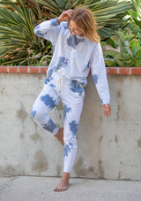 [Color: Ink Combo] A woman standing outside wearing a classic cotton jogger pant in a splatter tie dye wash. Featuring a drawstring waistband, side pockets, and a slim leg.