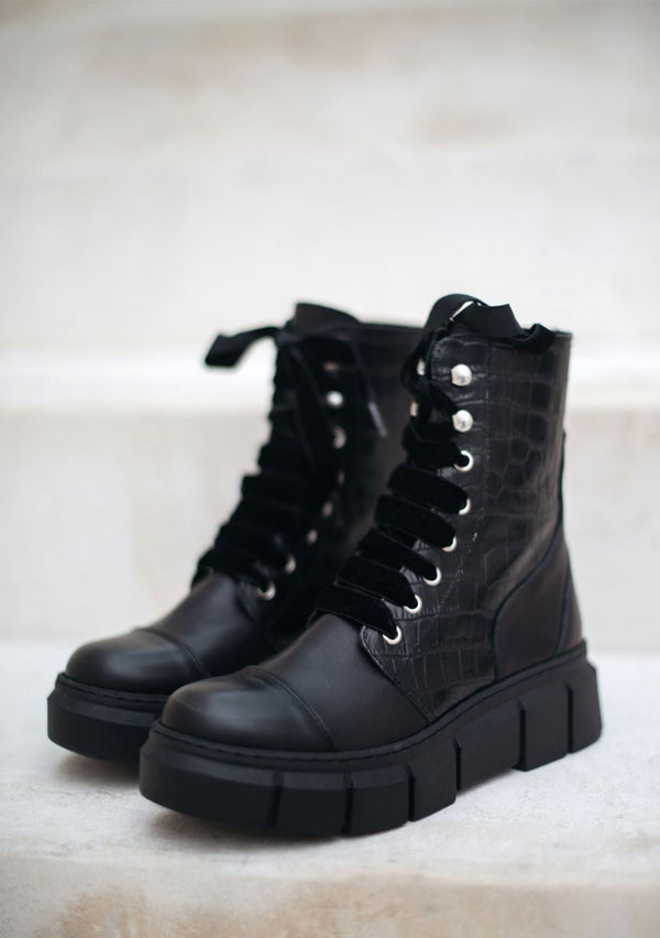 [Color: Black] Alohas black combat boots with crocodile embossed leather, a rubber sole, and lace up front.