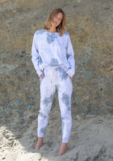 [Color: Grey Combo] A woman standing outside wearing a classic cotton jogger pant in a splatter tie dye wash. Featuring a drawstring waistband, side pockets, and a slim leg.