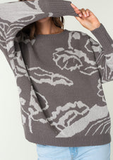 [Color: Charcoal/Silver] A close up front facing image of a brunette model wearing a bohemian cotton grey sweater with a silver floral motif. With long sleeves and a crew neckline.