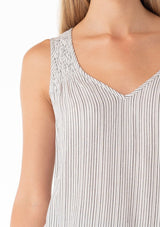 [Color: Off White/Black] A close up front facing image of a blonde model wearing a casual bohemian spring tank top in an off white and black stripe. With a v neckline, a smocked yoke detail, and a relaxed fit. 
