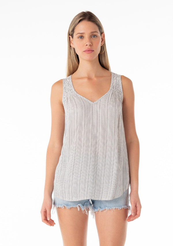 [Color: Off White/Black] A front facing image of a blonde model wearing a casual bohemian spring tank top in an off white and black stripe. With a v neckline, a smocked yoke detail, and a relaxed fit. 