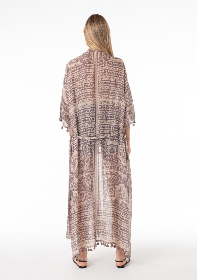 [Color: Natural/Grey] A back facing image of a blonde model wearing a bohemian lounge duster kimono robe in a grey mixed floral print. With short kimono sleeves, a tassel trimmed hemline, an open front, and a tie waist belt. 