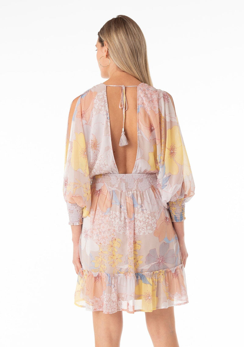 [Color: Natural/Blue] A back facing image of a blonde model wearing a best selling bohemian mini dress designed in a pink and blue floral print. With long split sleeves, a flowy tiered skirt, a smocked elastic waist, a v neckline, and an open back with tassel tie closure. 