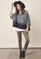 [Color: Charcoal/Midnight] A model wearing a relaxed grey dyed sweatshirt with a scoop neckline, long batwing sleeves, and raw edge finish details. 