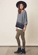 [Color: Charcoal/Midnight] A model wearing a relaxed grey dyed sweatshirt with a scoop neckline, long batwing sleeves, and raw edge finish details. 