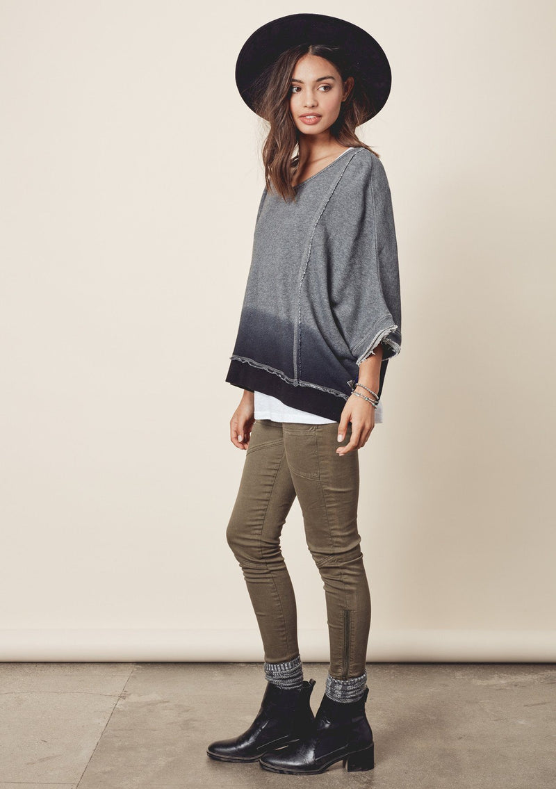 [Color: Charcoal/Midnight] A model wearing a relaxed grey dyed sweatshirt with a scoop neckline, long batwing sleeves, and raw edge finish details. 