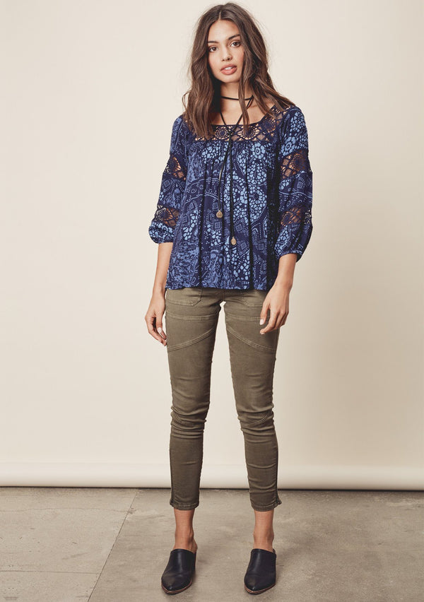 [Color: Midnight/Blue] A front facing image o a brunette model wearing a blue bohemian blouse with crochet lace trims. 