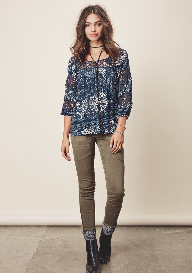 [Color: Teal/Vanilla] A front facing image of a brunette model wearing a teal  bohemian blouse with crochet lace trims. 