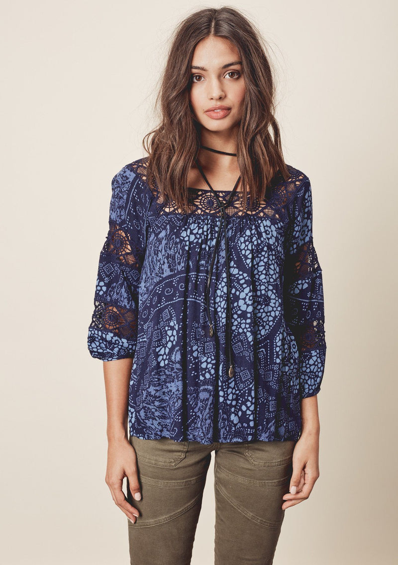 [Color: Midnight/Blue] A front facing image o a brunette model wearing a blue bohemian blouse with crochet lace trims. 