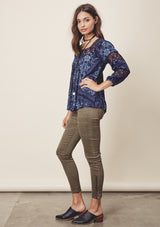 [Color: Midnight/Blue] A side facing image o a brunette model wearing a blue bohemian blouse with crochet lace trims. 