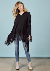 [Color: Black] A front facing image of a blonde model wearing a black suede fringed poncho. 