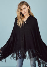 [Color: Black] A front facing image of a blonde model wearing a black suede fringed poncho.  