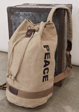 [Color: Beige] A blonde model wearing a cotton blend beige sack backpack with a drawstring closure. 