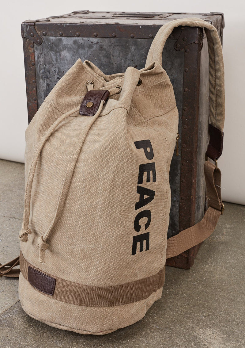 [Color: Beige] A blonde model wearing a cotton blend beige sack backpack with a drawstring closure. 