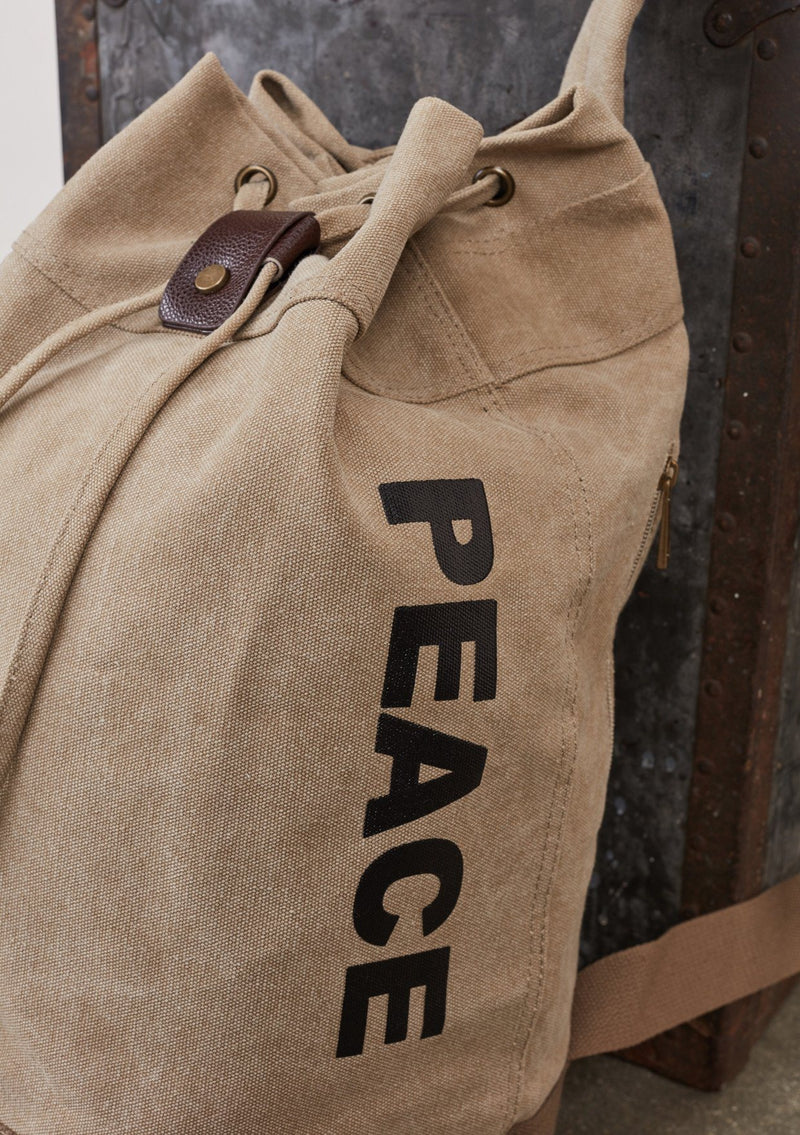 [Color: Beige] A cotton blend beige sack backpack with a drawstring closure. 