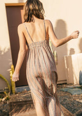 [Color: Red/Black] A woman outside wearing a striped sleeveless maxi dress with adjustable spaghetti straps with an o ring detail, an empire waist, and a v neckline. 