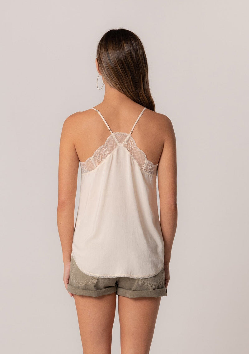 [Color: Vanilla] A back facing image of a brunette model wearing an ivory camisole tank top. With spaghetti straps, a v neckline, lace trim, a racerback, and a relaxed fit.