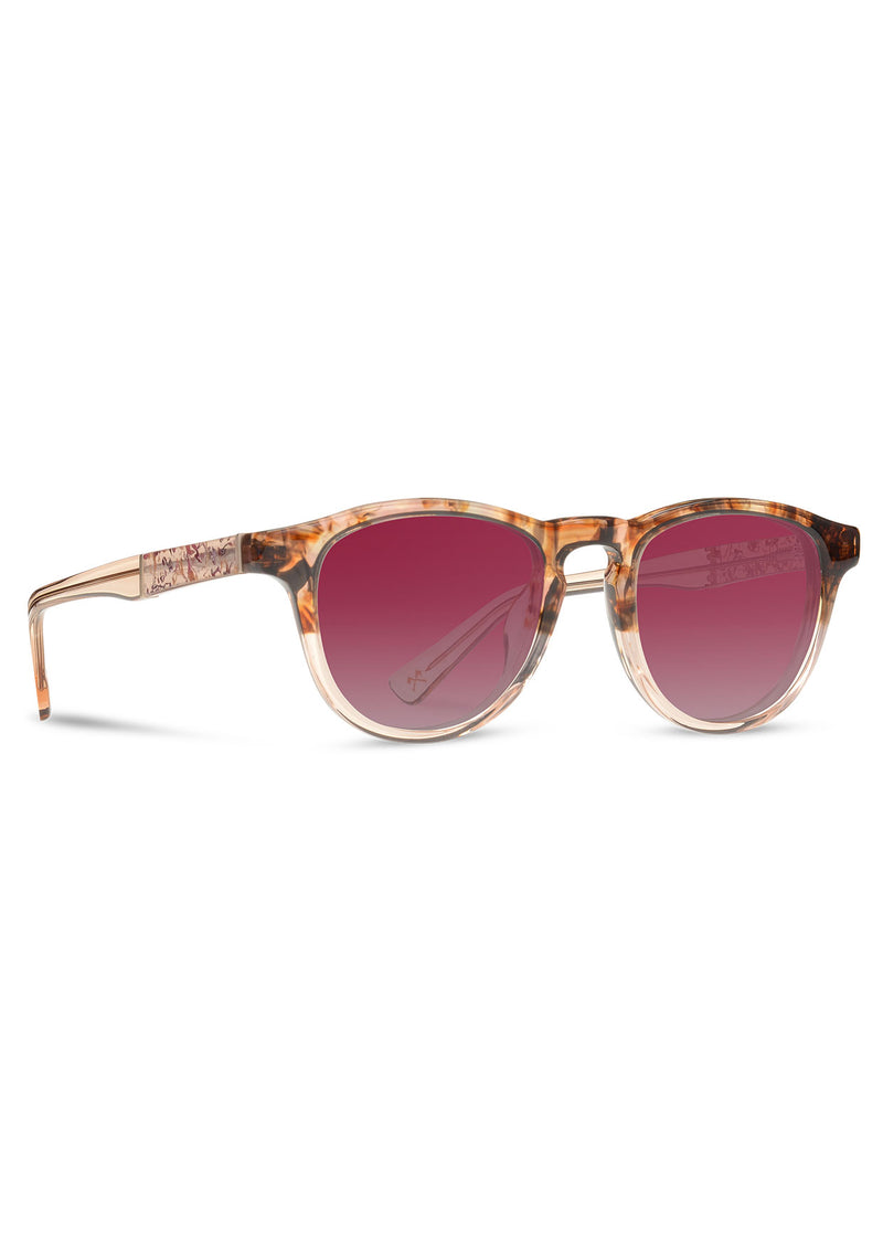 [Color: Low Tide] Sunglasses with a deep pink lens and a rose flower inlay. 